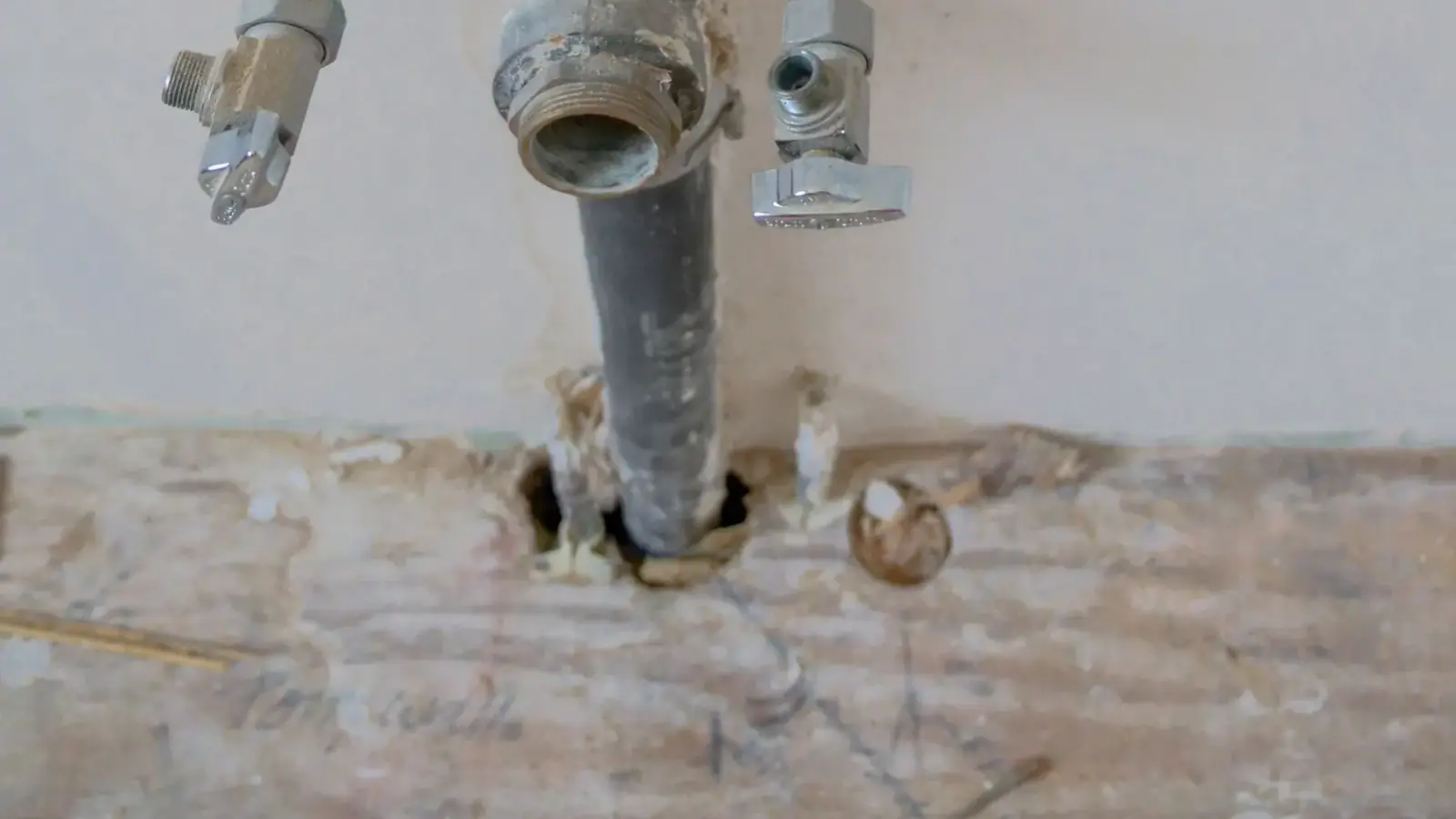 Freigelegte Sanitärleitungen und Anschlüsse in einer Wand