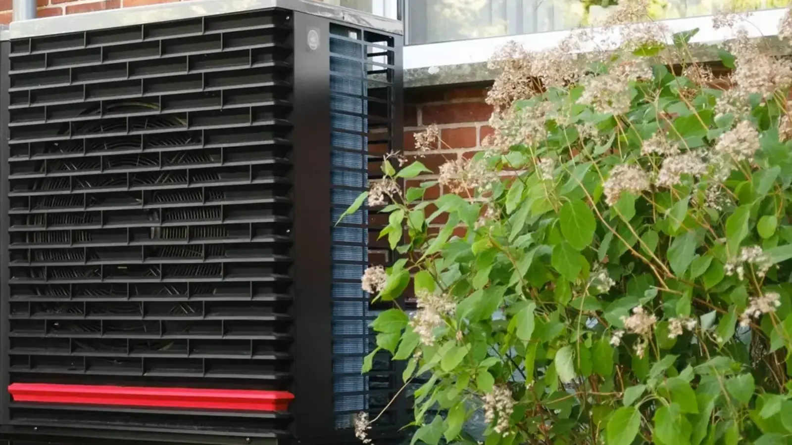 Moderne Luft-Wasser-Wärmepumpe neben einem Wohnhaus